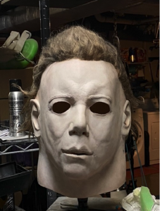 This is a Michael Myers Halloween movie mask that has been reahuled and he has a white face and brown hair.